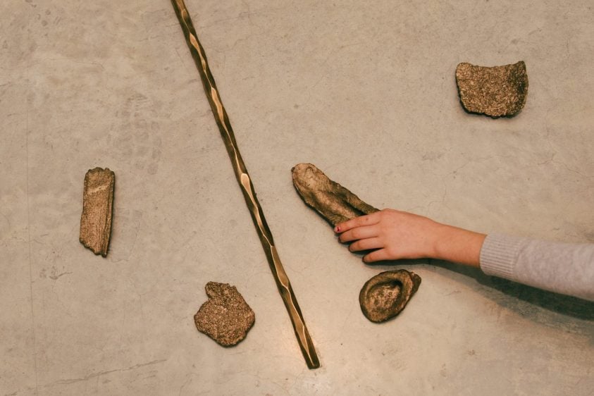 Brown objects on a grey floor with an arm extending and holding one