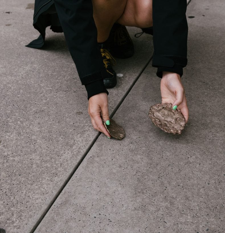 Person keeling and holding two rock-like objects