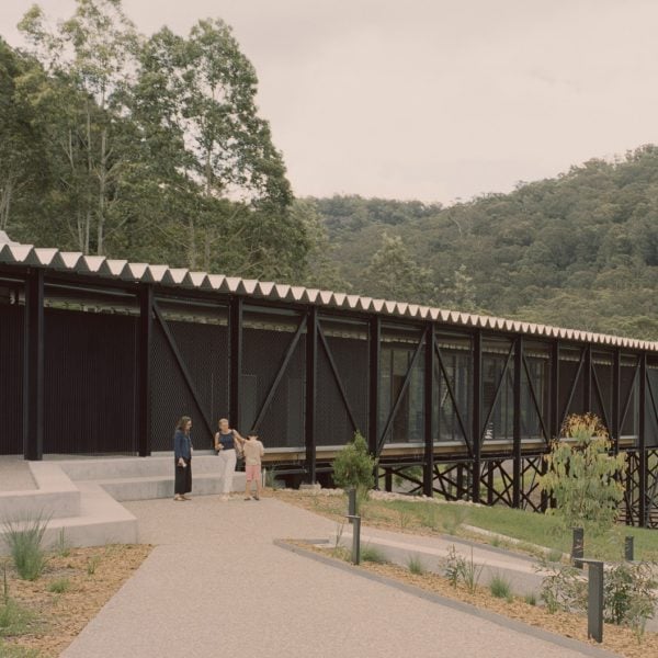 Black building extending over a gully, mountains in the background