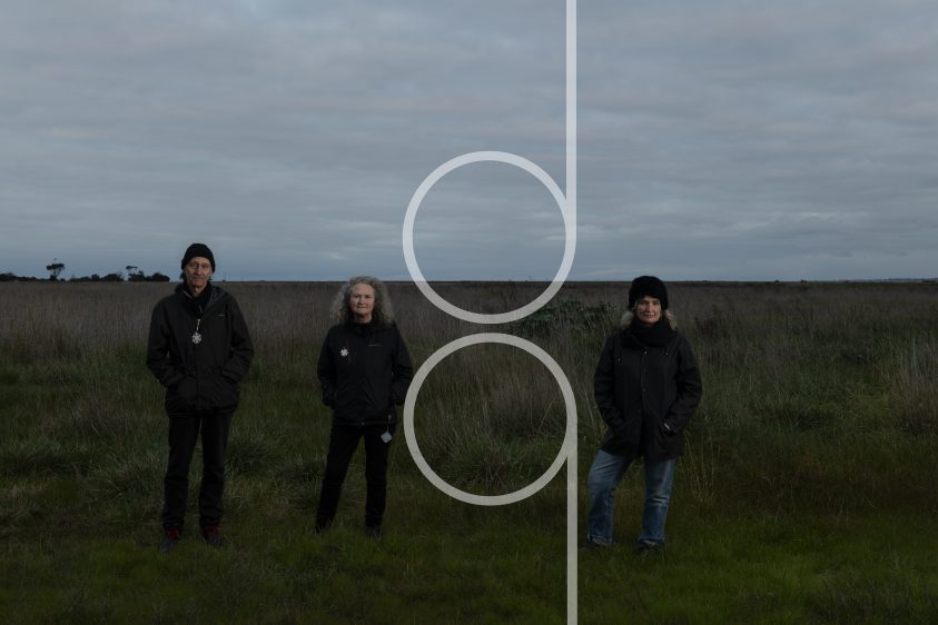 Three people standing in a grassy landscape