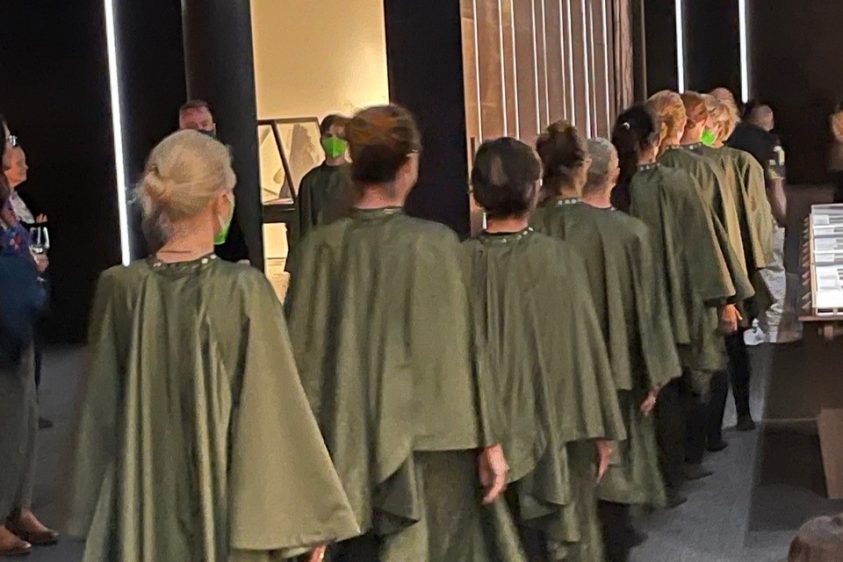 A line of 9 people wearing green cloaks