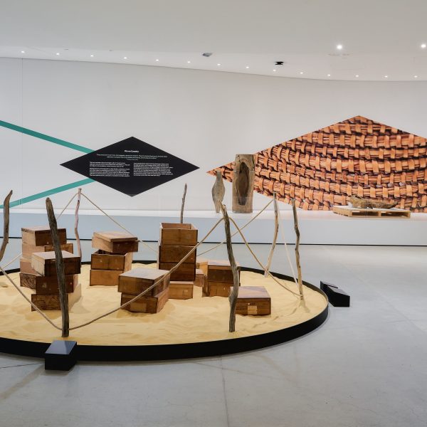Exhibition view ‘More Than a Tarrang (tree): Memory, Material and Cultural Agency’ at Bunjilaka Aboriginal Cultural Centre, Melbourne Museum, 2023, co-curated by Brian Martin, Brook Andrew, Kimberley Moulton and Jessica Neath. Artworks in view: Moorina Bonini, ‘Untitled (ethnographic container)’, 2023, installation. Brian Martin, ‘Culturally Modified Thulu: Methexical Countryscape Kamilaroi #1, 2022, charcoal on paper with cultural belongings from the Museums Victoria First Peoples Collection. Photo: Eugene Hyland.