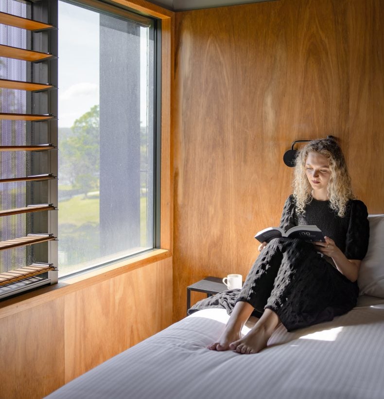 Woman sits on a bed in a cabin.