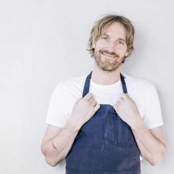 Man poses wearing blue chef's apron.