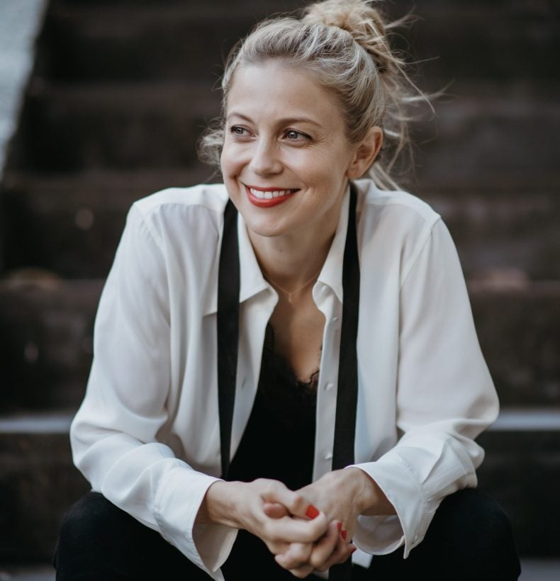 Woman smiles whilst sitting on outdoor steps.