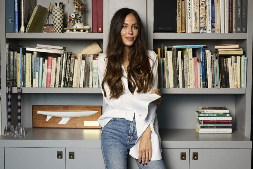 Natalie Kyriacou poses for the camera in front of a wall of book shelves.
