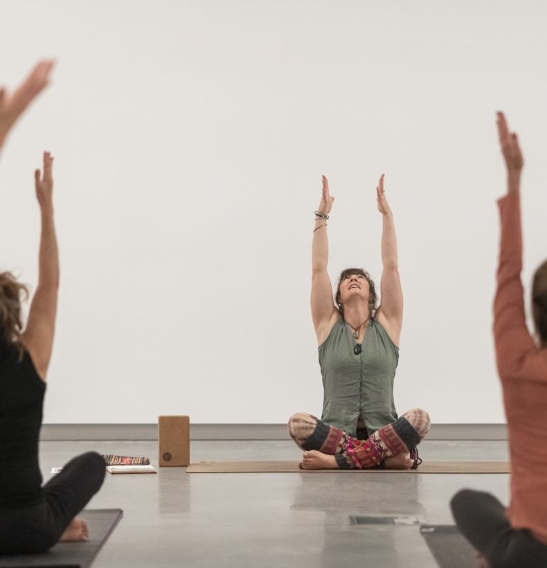 People doing yoga in a studio, with their hands up above their heads.