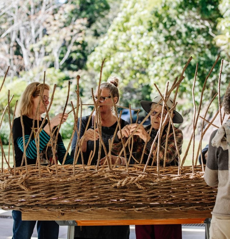 Women weaving a coffin from natural resources.