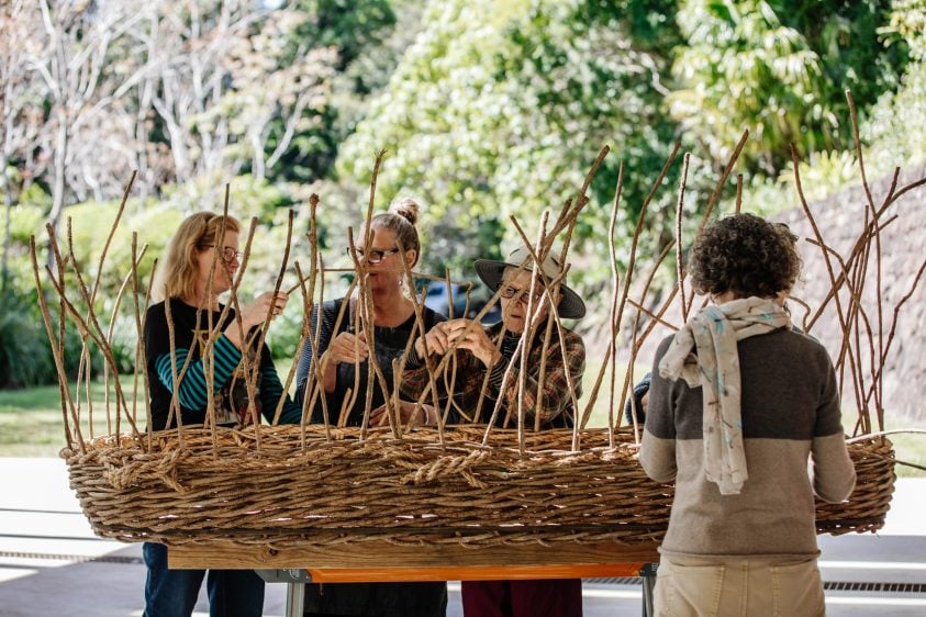 Women weaving a coffin from natural resources.