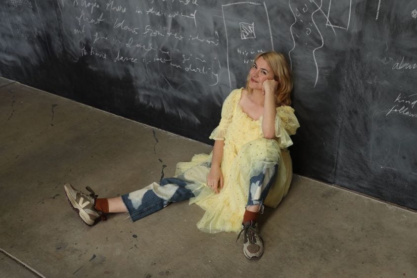 Woman sitting on the floor on a wall.