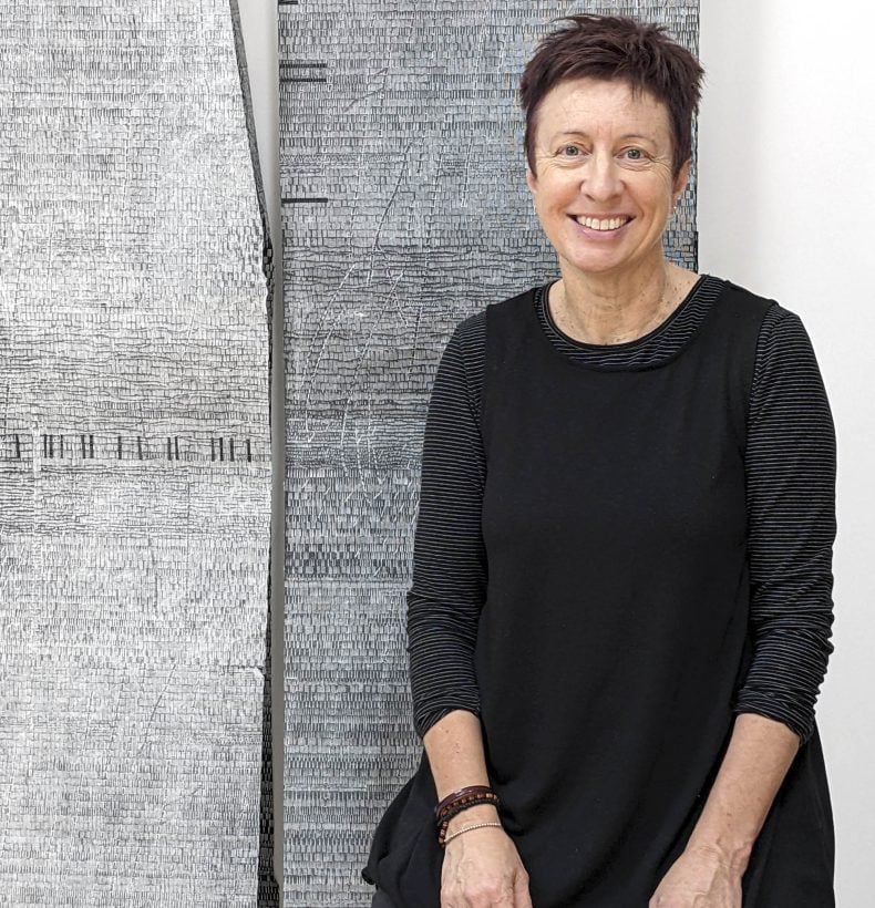 Portrait of Bridget Hillebrand standing next to artwork.