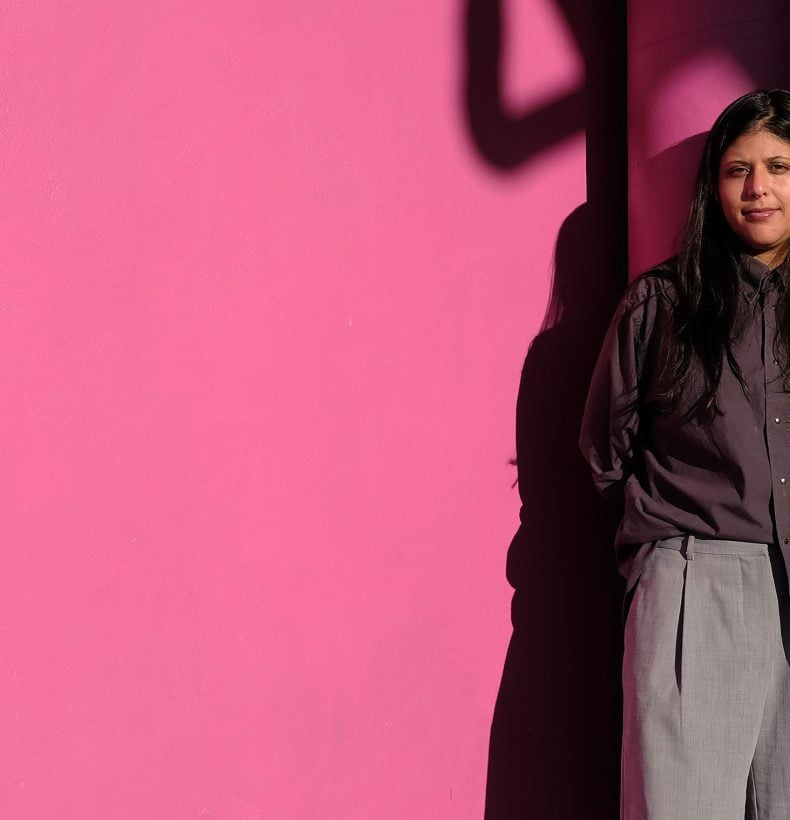 Claudia Nicholson standing on a pink wall in the sunshine.