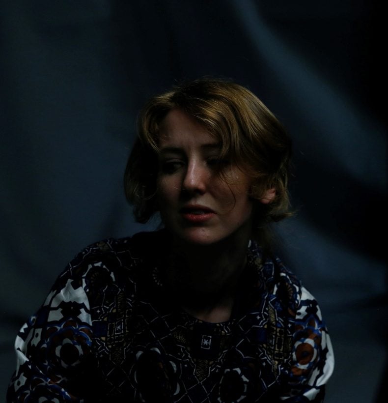 Dark studio shot of a woman looking down.