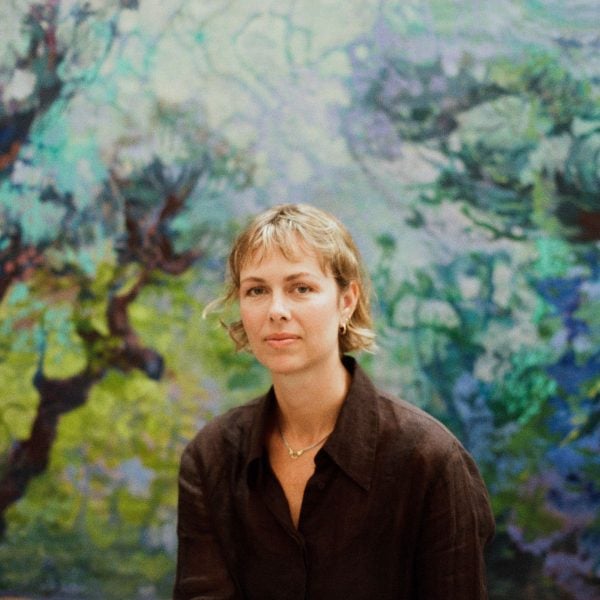 Blonde woman sits in front of artwork