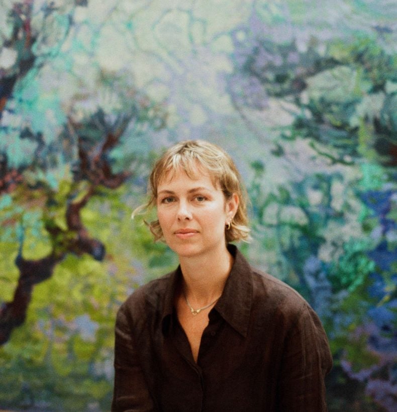Blonde woman sits in front of artwork