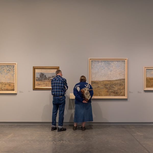Two people in blue read an art label