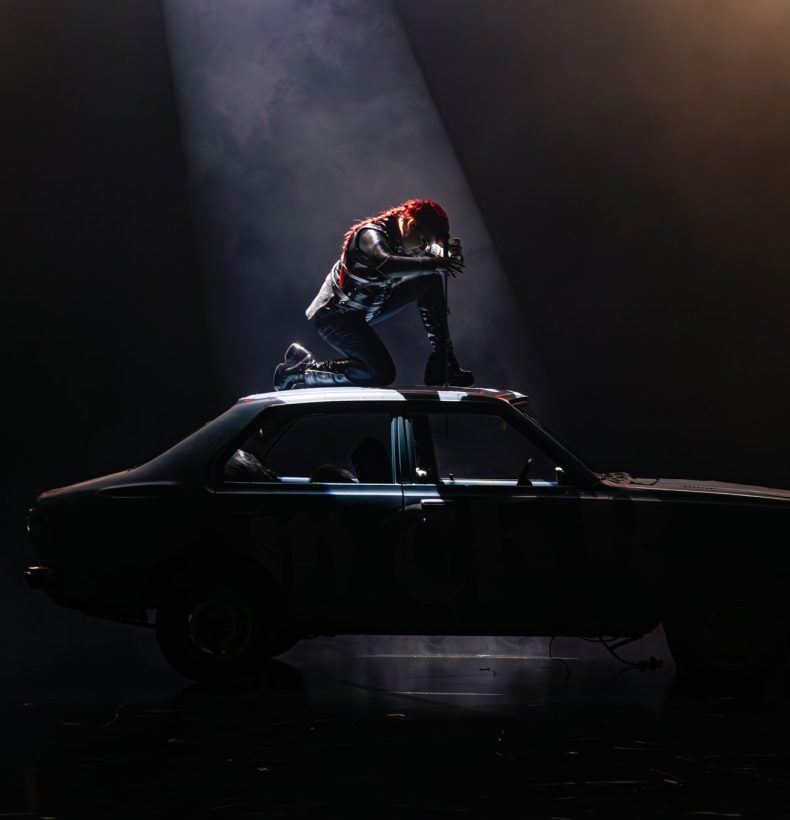 Performer onstage, atop a car