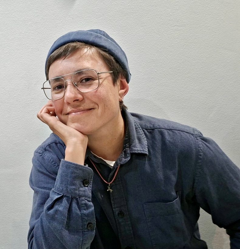 Person resting chin on hand, smiling at camera