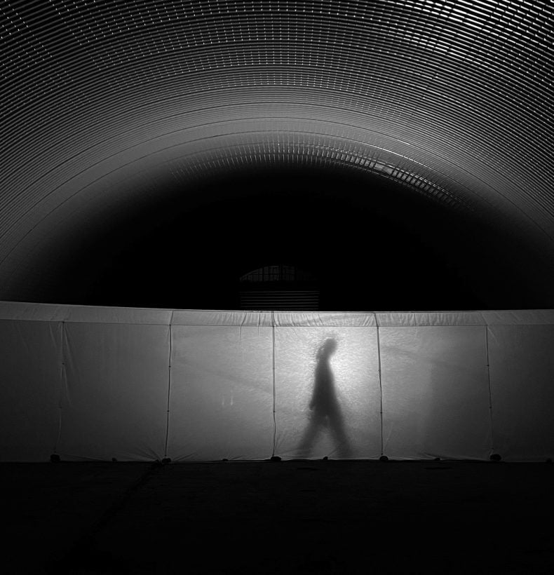 Person walking in shadow behind artwork